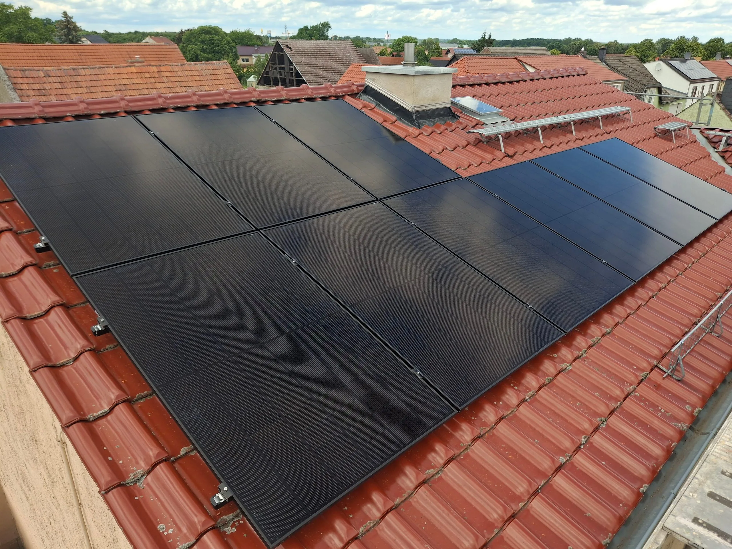 Nahaufnahme der schwarzen bifazialen Glas-Glas-Solarmodule auf einem roten Ziegeldach
