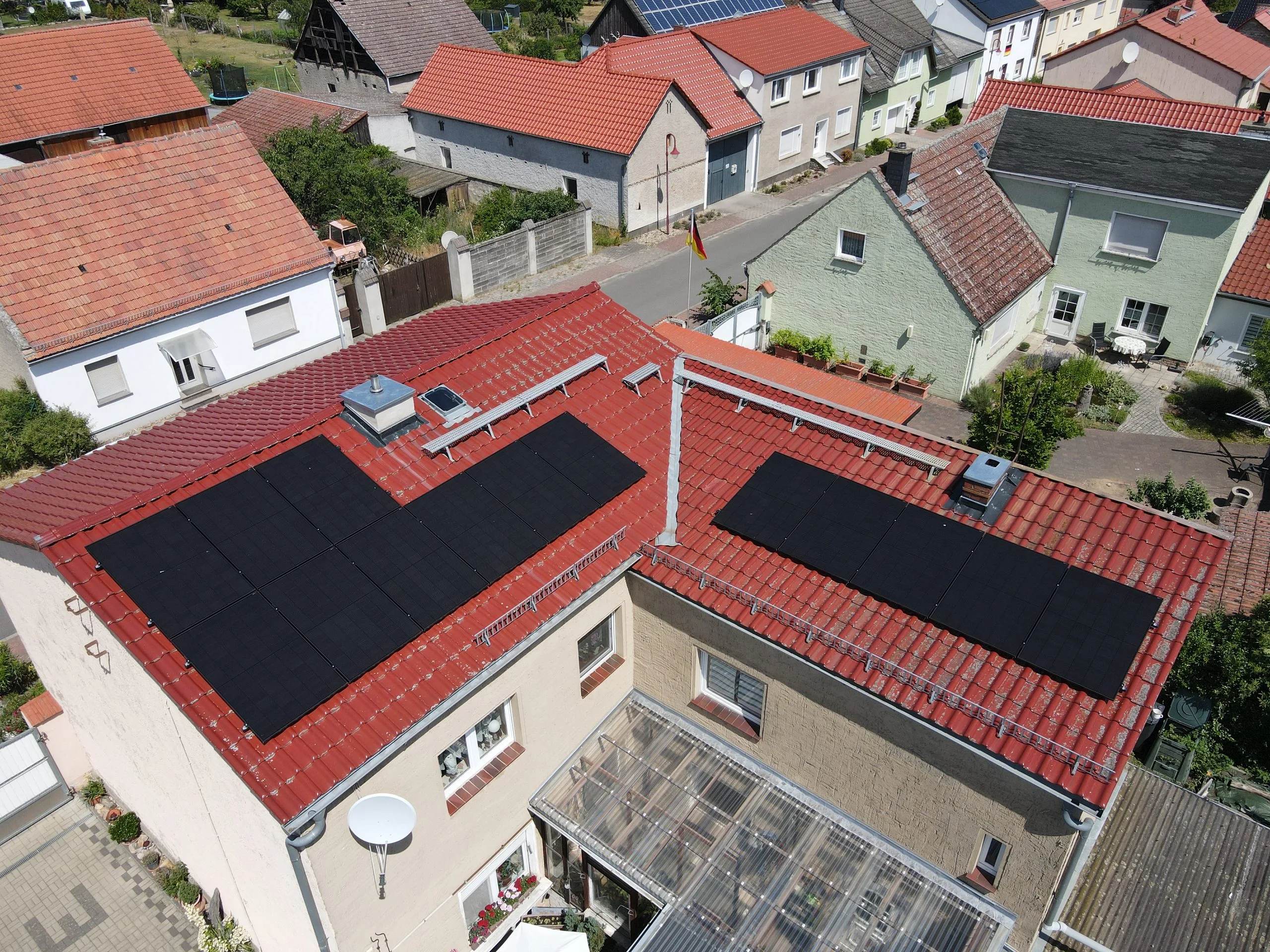 Photovoltaikanlage mit schwarzen Full-Black-Modulen auf zwei Ziegeldächern in Linthe, aufgenommen aus der Luft